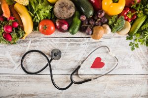 elevated-view-stethoscope-with-heart-shape-near-fresh-vegetables-wooden-desk